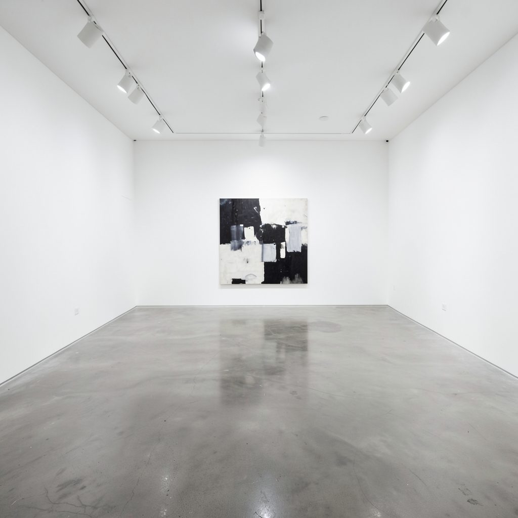 An empty white-walled gallery space with polished concrete floor, track lighting on the ceiling, one large abstract painting on the wall
